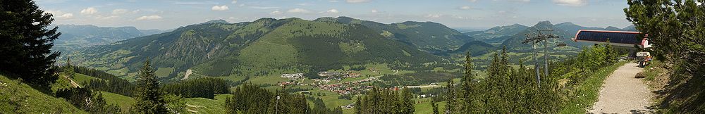 Blick vom Iseler auf Oberjoch in der Bildmitte, rechts an den Ort angrenzend das Kematsried-Moos und ganz rechts die Bergstation der Iselerbahn auf 1559 m Höhe. Der Gipfel mit dem Mast im Hintergrund links vom Ort ist der 1738 m hohe Grünten.