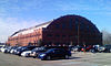 Exterieur eines großen Stadions mit einem halbrund angelegten Dach über dem Gebäude