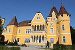 Schlossgebäude mit Torbogen, freistehendem Turm und Wirtschaftsgebäude