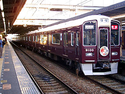 Zug der 9000er-Serie von Hankkyū in typisch dunkelrotem Anstrich beim Halt im Bahnhof