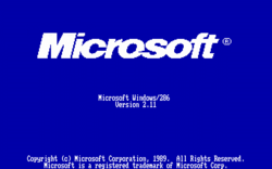 Startbildschirm von Windows 2.11 (deutsch): im oberen Bildteil groß das „neue“ (noch aktuelle) Logo "Microsoft (R)" (kursiv), in der Mitte in kleinerer „Computerschrift“ die Versionsangaben und am unteren Bildschirmrand die Urheberrechtsvermerke; alles zentriert gehalten