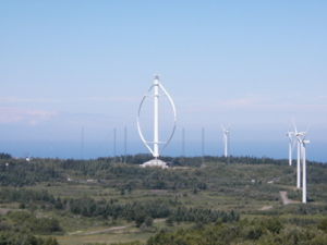 Der Darrieusrotor Éole. Seine Größe wird im Vergleich mit den Bäumen und den anderen Windrädern ersichtlich.