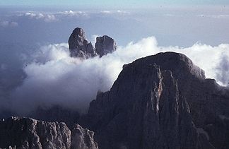 Cima della Madonna (etwa in Bildmitte rechts des scheinbar höchsten Gipfels, dem Sass Maor) von der Pala di San Martino. Rechts der Bildmitte die Cima di Ball und davor der Campanile Pradidali