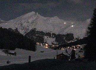 Schiahorn aus Südost bei Vollmond, über Davos Dorf (aus Richtung Dischmatal). Die hellen Lichter rechts am Berg sind Pistenbearbeitungsmaschinen im Parsenngebiet, links ebenfalls ein solches Licht im Schnee über der Schatzalp.