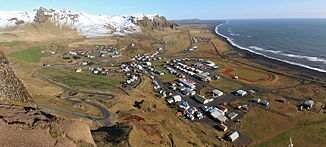 Luftbild von Vík í Mýrdal, im Hintergrund vor dem Inselberg Hjörleifshöfði die Mündung des Múlavkísl