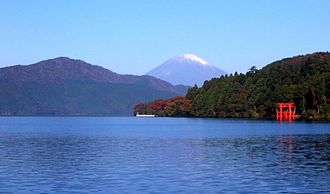 Aufnahme des Ashi-Sees von dessen Südostseite. Im Hintergrund ist der Fujisan zu erkennen, rechts das rote Torii des Hakone-Schreins.