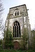 Ein dreistufiger Turm; im unteren Abschnitt ist eine Türe, darüber in der Mitte ein großes Fenster und im oberen Abschnitt befindet sich die Öffnung für die Glocken.