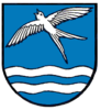Das Miedelsbacher Wappen zeigt eine fliegende Schwalbe und zwei Wellenbalken in weiß (silber) auf blauem Grund.